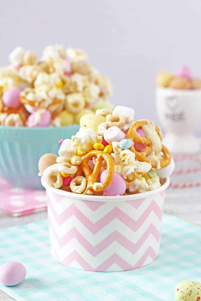 Easter Trail Mix served in a patterned pink and white cardboard cup and a blue and white gingham napkin.