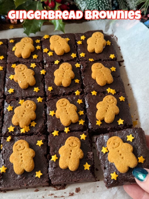 A tray of Gingerbread Brownies cut into small squares and decorated with mini gingerbread men and small gold edible stars.