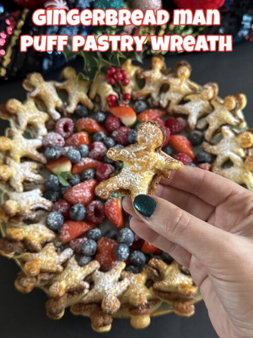 A puff pastry wreath made up of mini gingerbread men with a Nutella filling, with fresh berries in the middle and a dusting of icing sugar.